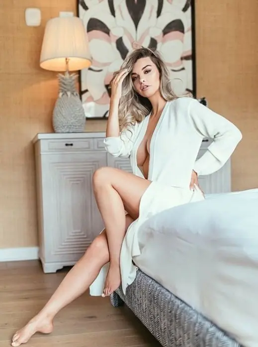 Emily op een hotelbed, in een nonchalante badjas – een ‘morning-after’-sfeer met een topescort uit Amsterdam