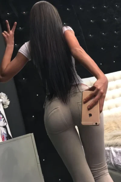 brunette escort Amsterdam Svetlana back view tight dress long straight hair curves highlighted indoor setting